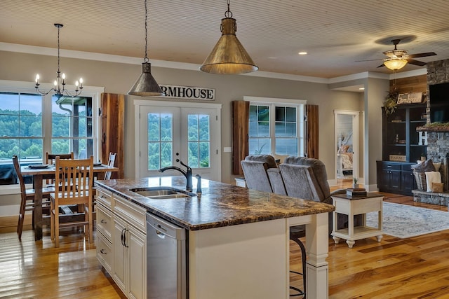 kitchen featuring plenty of natural light, open floor plan, stainless steel dishwasher, and a sink