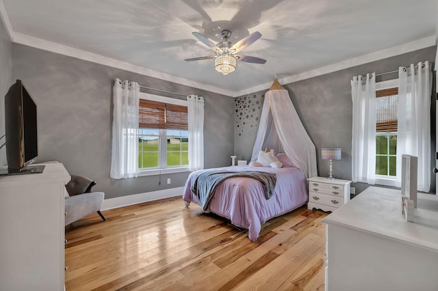 bedroom featuring light wood-type flooring, a ceiling fan, baseboards, and ornamental molding