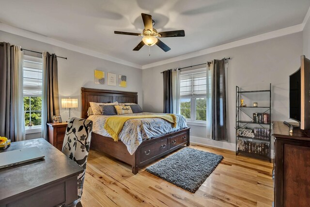 bedroom featuring light wood-type flooring, ornamental molding, and ceiling fan