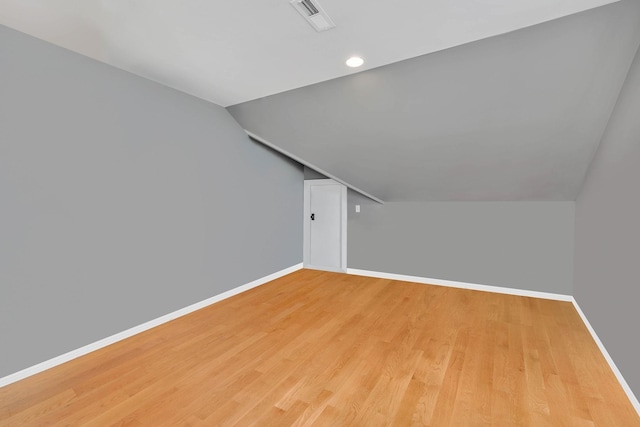 additional living space featuring lofted ceiling, baseboards, light wood-style flooring, and visible vents