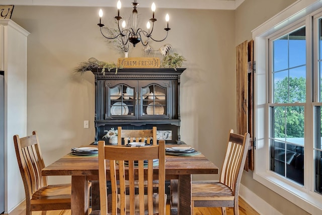 dining space with baseboards, light wood-style floors, a notable chandelier, and a healthy amount of sunlight
