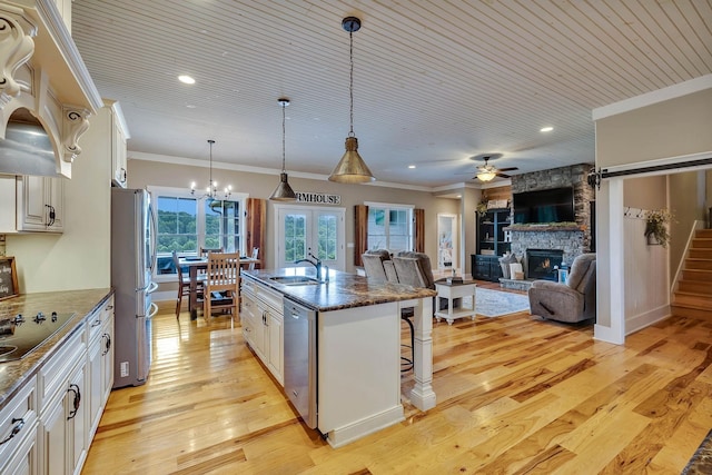 kitchen with ornamental molding, a sink, a fireplace, a kitchen bar, and appliances with stainless steel finishes