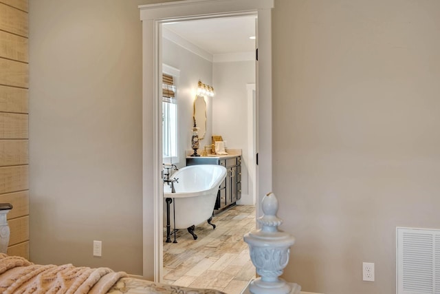 full bathroom featuring a freestanding tub, wood finished floors, visible vents, and ornamental molding