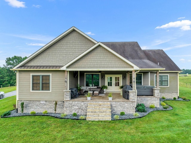 rear view of property featuring french doors, stone siding, outdoor lounge area, a patio area, and a yard