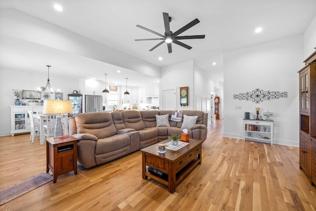 living area featuring recessed lighting, light wood-style flooring, and ceiling fan with notable chandelier