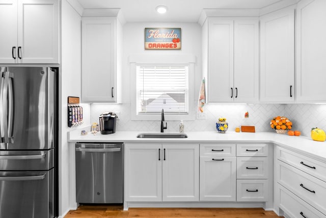 kitchen with appliances with stainless steel finishes, a sink, white cabinetry, and light countertops