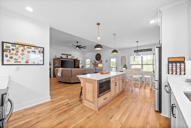 kitchen with light brown cabinetry, light countertops, appliances with stainless steel finishes, and light wood-type flooring