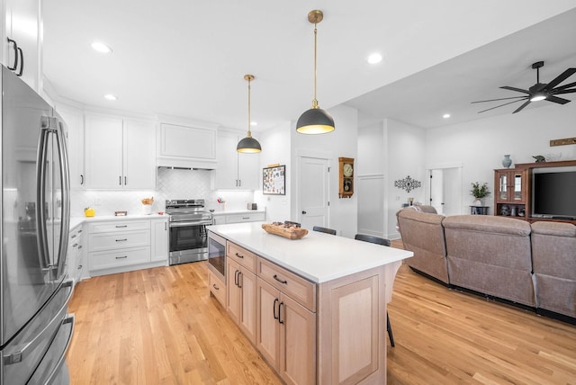 kitchen with open floor plan, appliances with stainless steel finishes, tasteful backsplash, and light wood finished floors