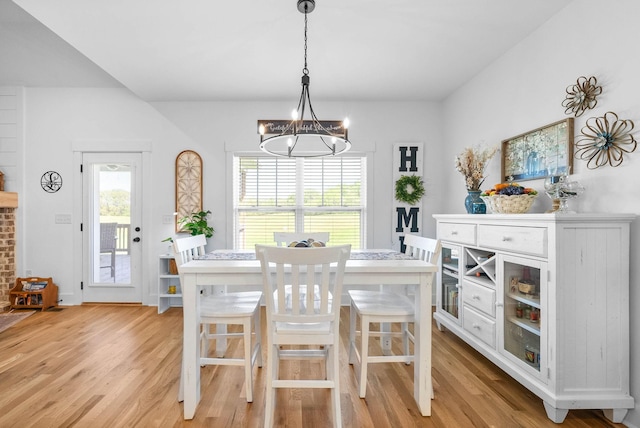 dining area with a wealth of natural light, light wood finished floors, and an inviting chandelier