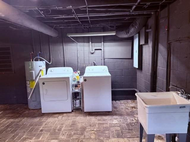 washroom with a sink, separate washer and dryer, water heater, brick floor, and laundry area