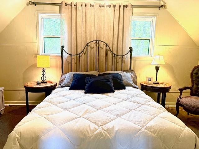 bedroom with dark wood finished floors, lofted ceiling, and baseboards