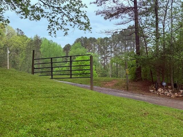 view of gate with a forest view and a lawn