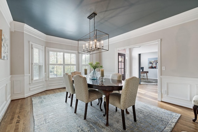 dining space with crown molding, a healthy amount of sunlight, a wainscoted wall, and a notable chandelier