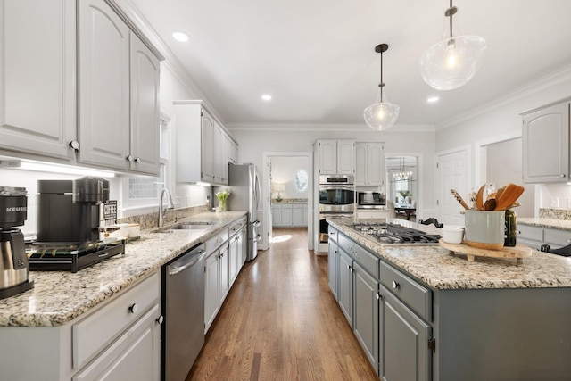 kitchen with stainless steel appliances, a sink, white cabinetry, gray cabinets, and a kitchen island