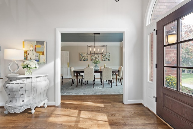 entryway featuring baseboards, wood finished floors, and a chandelier