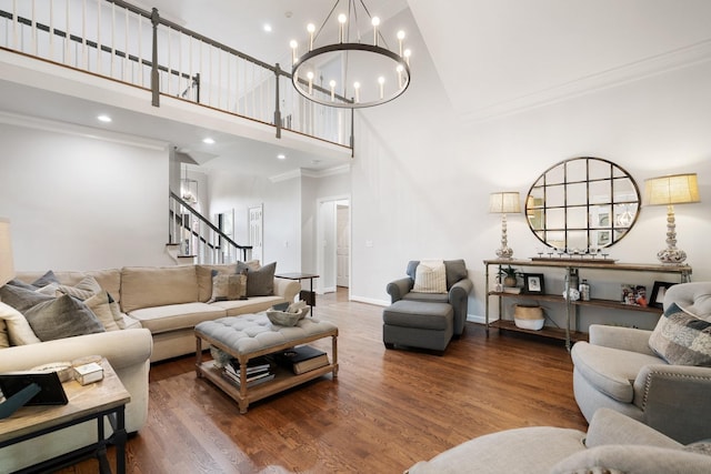 living room featuring stairway, crown molding, wood finished floors, a chandelier, and a towering ceiling