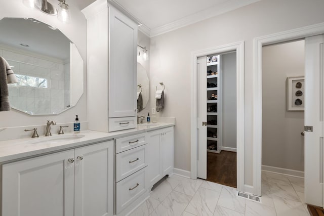 full bathroom featuring marble finish floor, double vanity, crown molding, and a sink