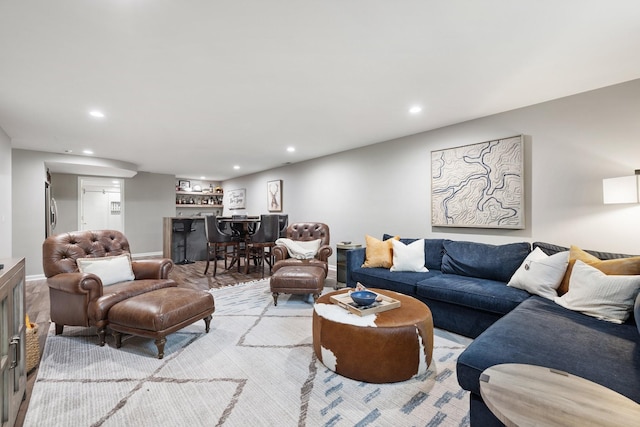 living room featuring indoor bar, wood finished floors, baseboards, and recessed lighting