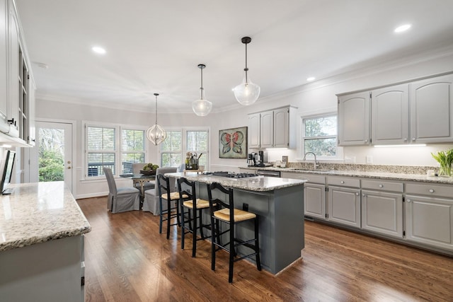 kitchen with a kitchen bar, ornamental molding, and light stone counters