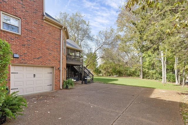 view of side of home featuring stairs, driveway, a lawn, brick siding, and a garage