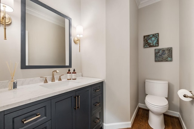 bathroom featuring wood finished floors, toilet, vanity, ornamental molding, and baseboards