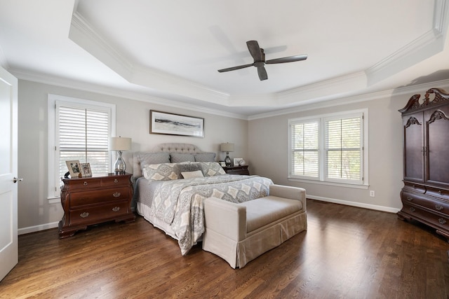 bedroom with dark wood-type flooring, a raised ceiling, baseboards, and ornamental molding