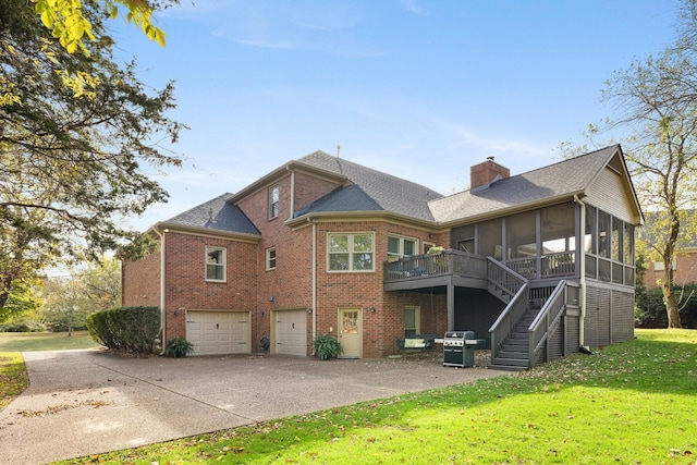 back of property with a lawn, a sunroom, brick siding, and concrete driveway