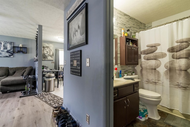 bathroom featuring wood finished floors, a textured ceiling, toilet, and vanity