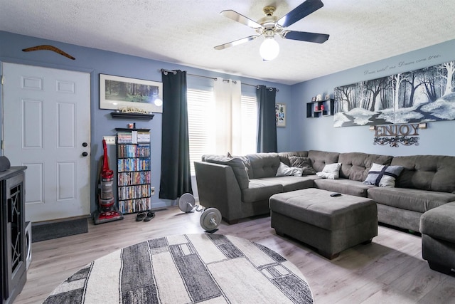 living area with light wood-type flooring, a ceiling fan, and a textured ceiling