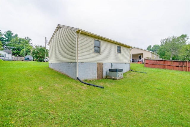 view of side of home with a yard and fence