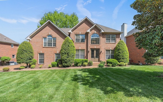 colonial-style house with central AC, brick siding, french doors, and a front lawn