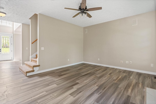 spare room featuring a ceiling fan, stairway, wood finished floors, and baseboards
