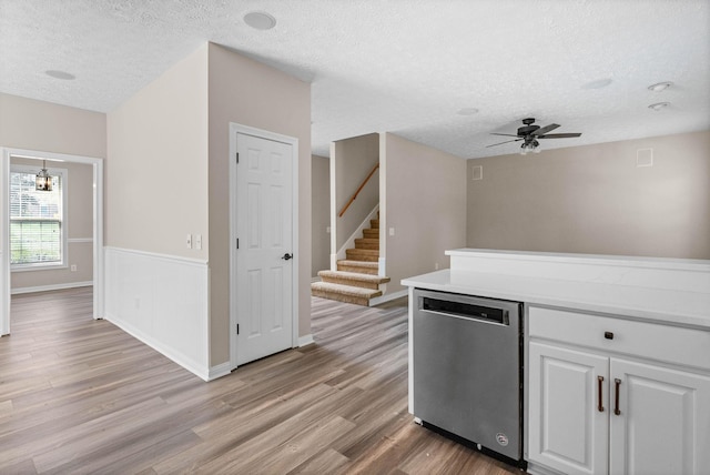 kitchen with a ceiling fan, stainless steel dishwasher, a textured ceiling, and light wood-style flooring