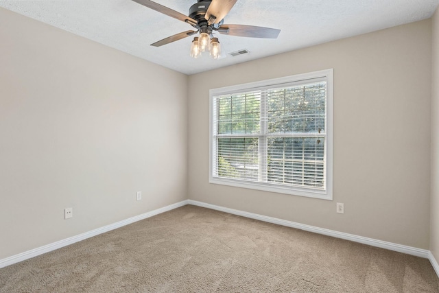 spare room with a ceiling fan, visible vents, carpet floors, and baseboards