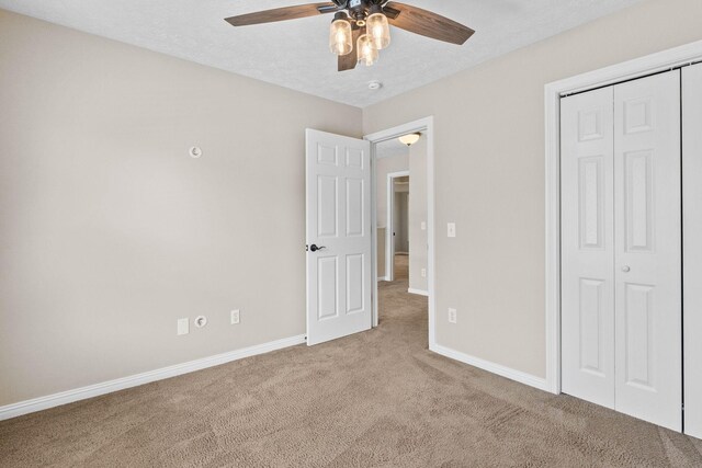 unfurnished bedroom featuring a closet, carpet flooring, a ceiling fan, and baseboards