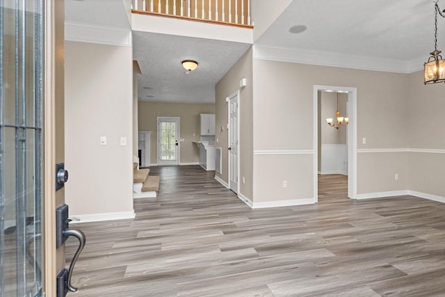 entryway featuring baseboards, wood finished floors, an inviting chandelier, and ornamental molding
