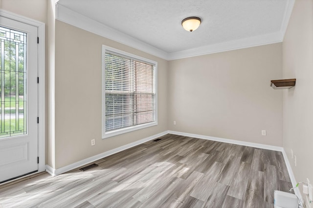 foyer with baseboards, visible vents, wood finished floors, and crown molding