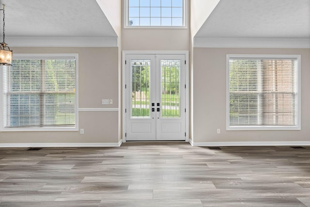 foyer featuring a textured ceiling, an inviting chandelier, wood finished floors, and plenty of natural light