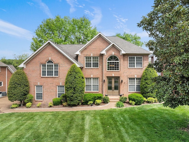 colonial home featuring a front lawn, french doors, and brick siding