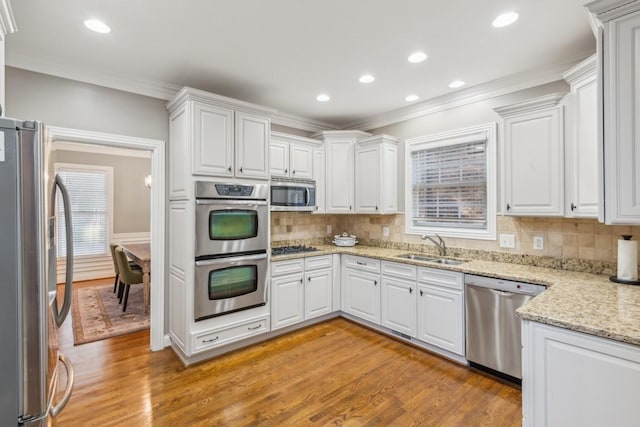 638 Band Dr, Franklin, TN 37064 - kitchen featuring appliances with stainless steel finishes, crown molding, white cabinetry, light wood-style flooring, and recessed lighting