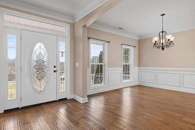 entryway featuring hardwood / wood-style flooring, visible vents, a chandelier, and crown molding