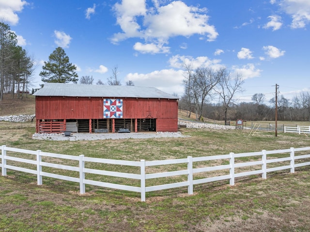 view of outbuilding featuring a rural view, an outbuilding, and fence