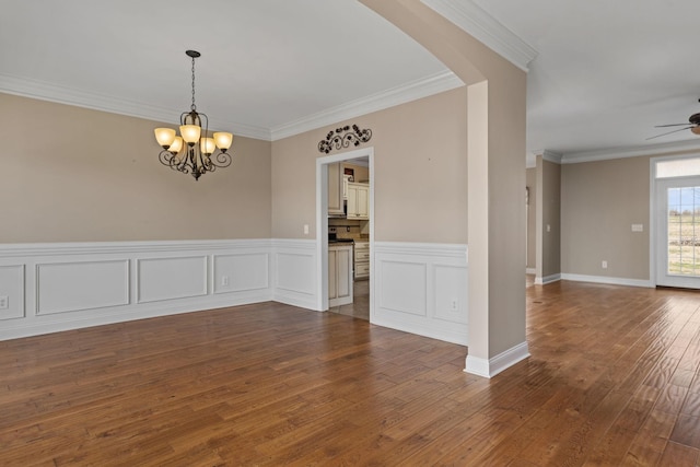spare room with dark wood-type flooring, arched walkways, crown molding, and ceiling fan with notable chandelier