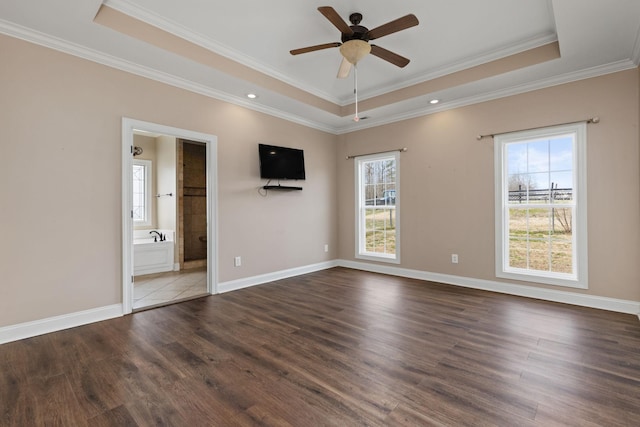 unfurnished bedroom featuring a tray ceiling, wood finished floors, and crown molding