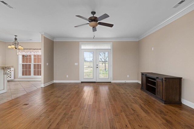 unfurnished living room featuring wood finished floors, visible vents, ornamental molding, and ceiling fan with notable chandelier