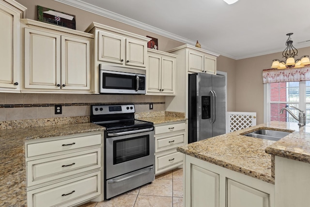 kitchen with cream cabinetry, a sink, crown molding, hanging light fixtures, and appliances with stainless steel finishes