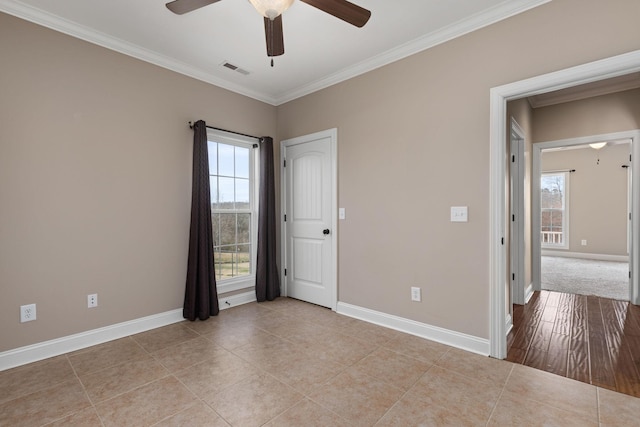 spare room featuring crown molding, baseboards, ceiling fan, and a healthy amount of sunlight