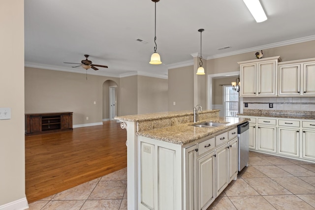 kitchen featuring arched walkways, stainless steel dishwasher, crown molding, and a sink