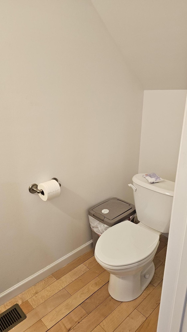 bathroom with visible vents, baseboards, wood finished floors, and toilet