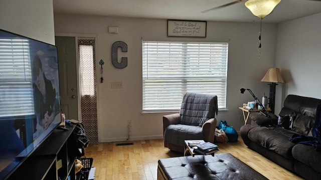 living area with ceiling fan, baseboards, light wood-style floors, and visible vents